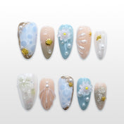 Blue and nude press-on nails with 3D seashell design, white flowers, and pearl accents