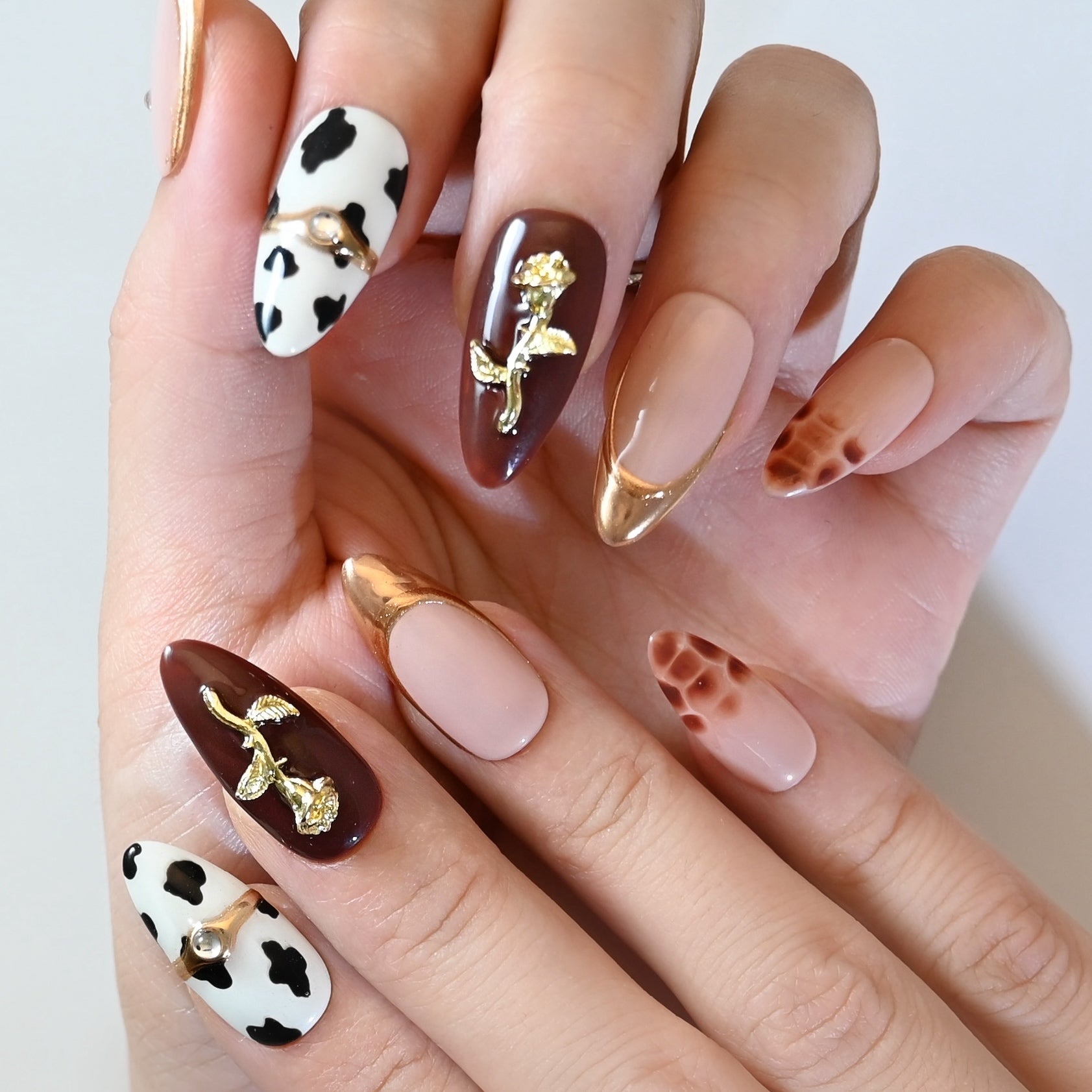Burgundy and nude press-on nails with metallic gold tips and floral embellishments