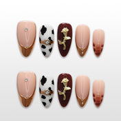 Cow print press-on nails with gold French tips, rhinestones, and 3D rose charm