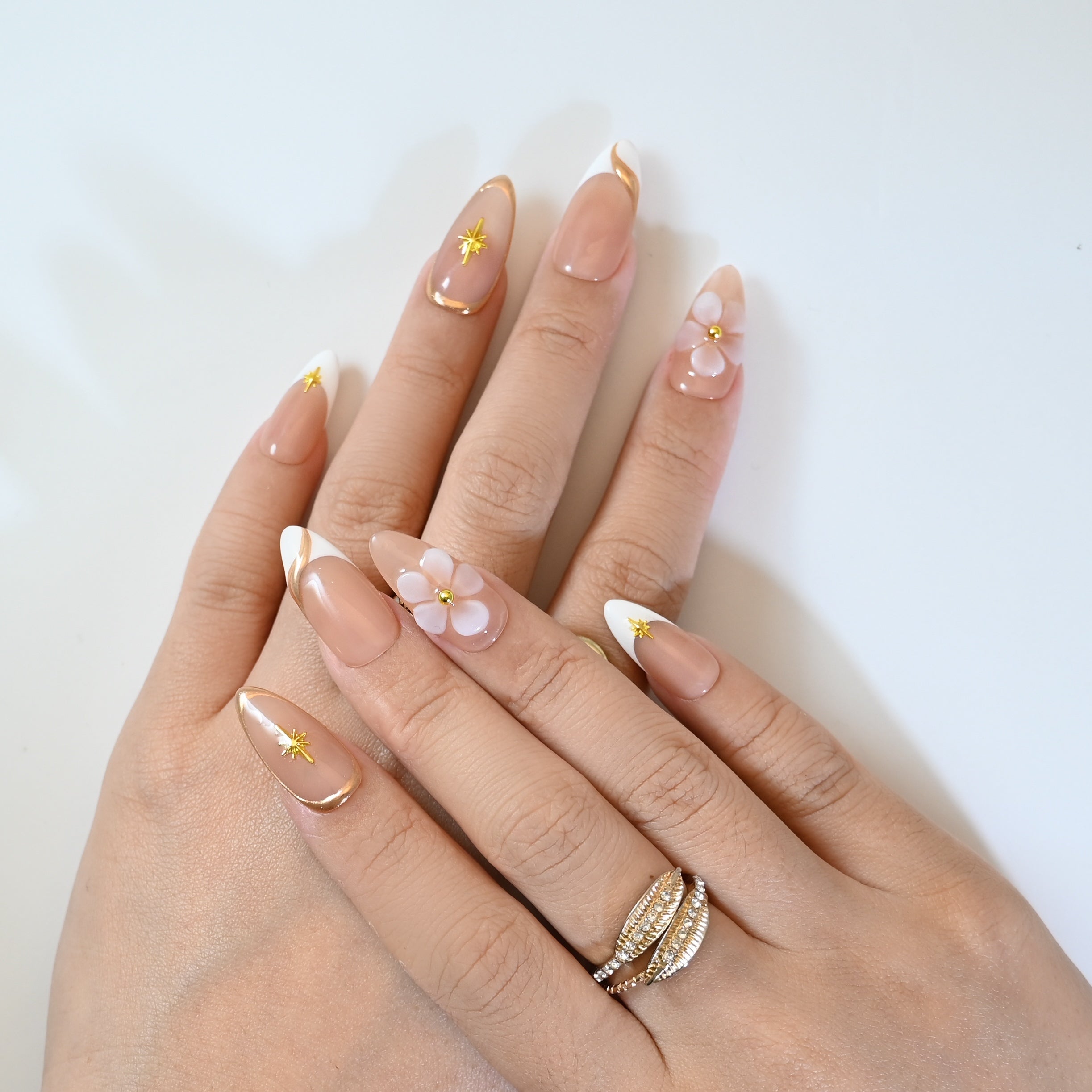 Elegant nude press-on nails with gold star embellishments and white tips