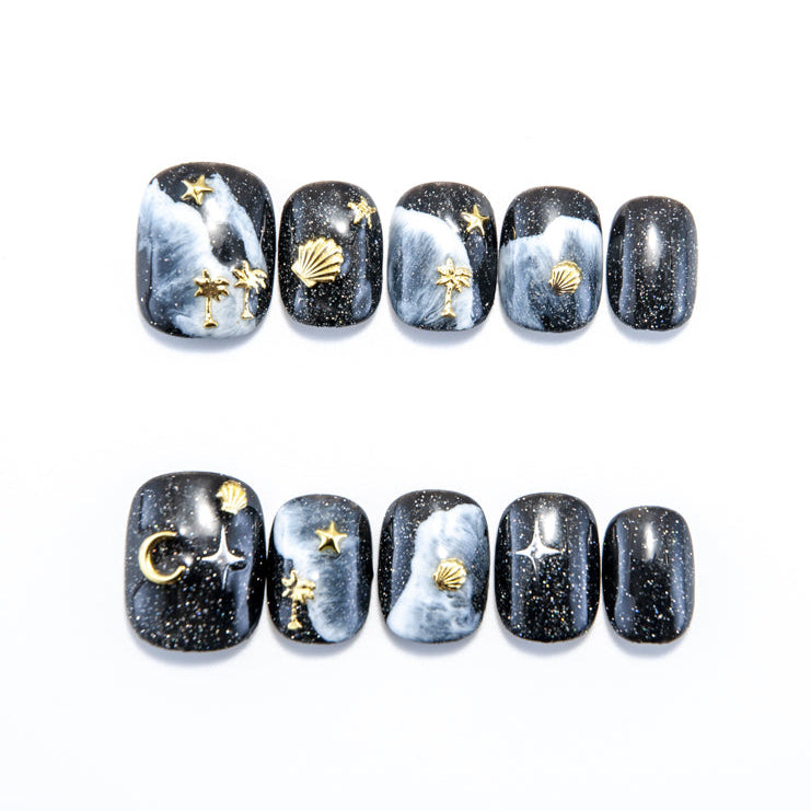 Galaxy black press-on toenails with gold seashell, palm tree, and moon charms
