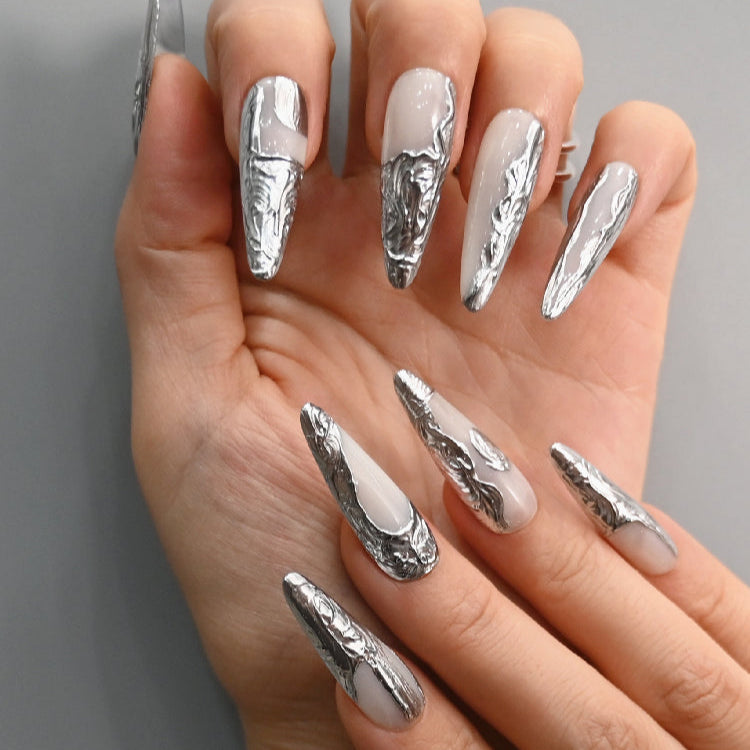 Handmade metallic nails with silver sculpted texture on a glossy white base