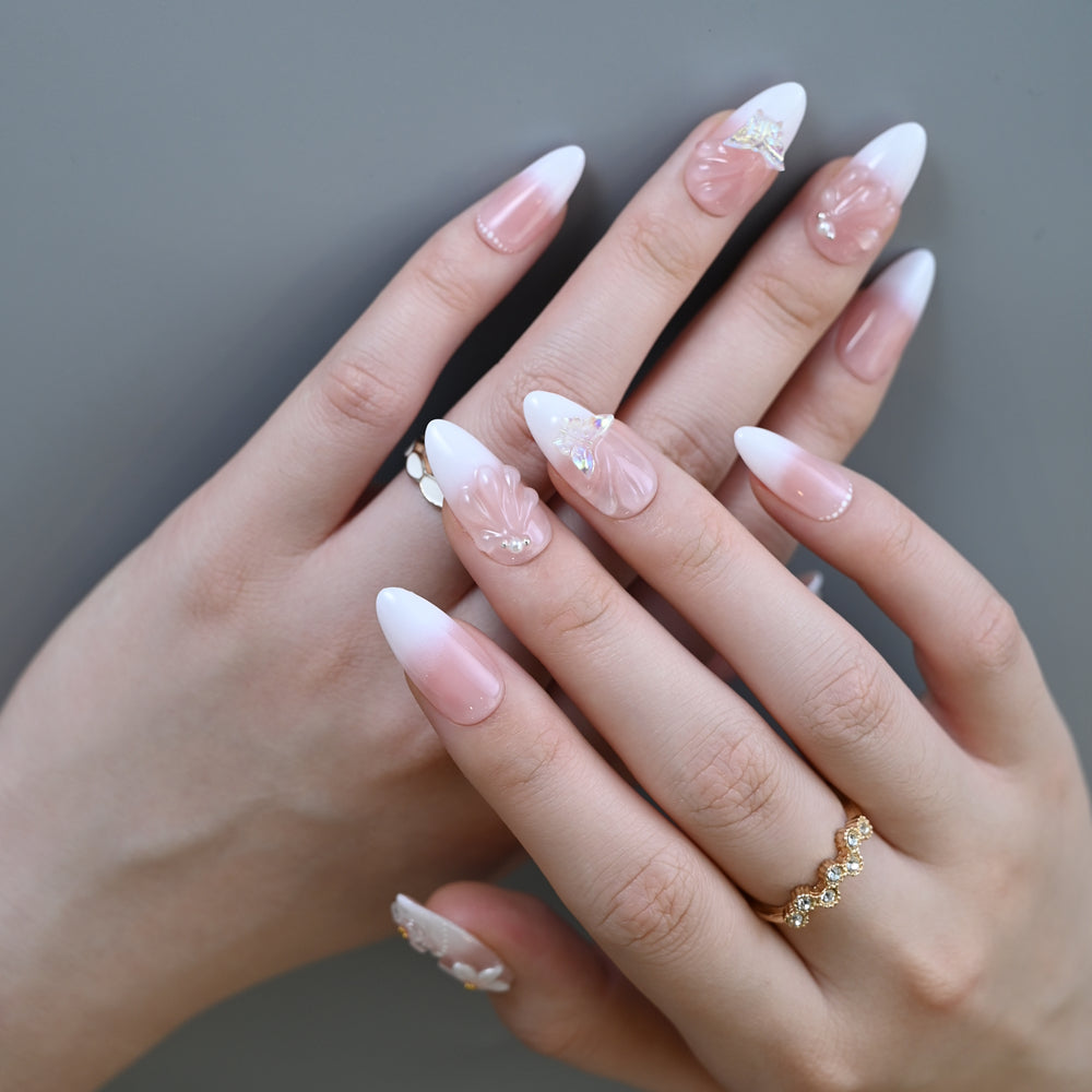 Soft pastel press-on nails with white blossoms, gems, and sculpted details