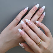 Soft pastel press-on nails with white blossoms, gems, and sculpted details