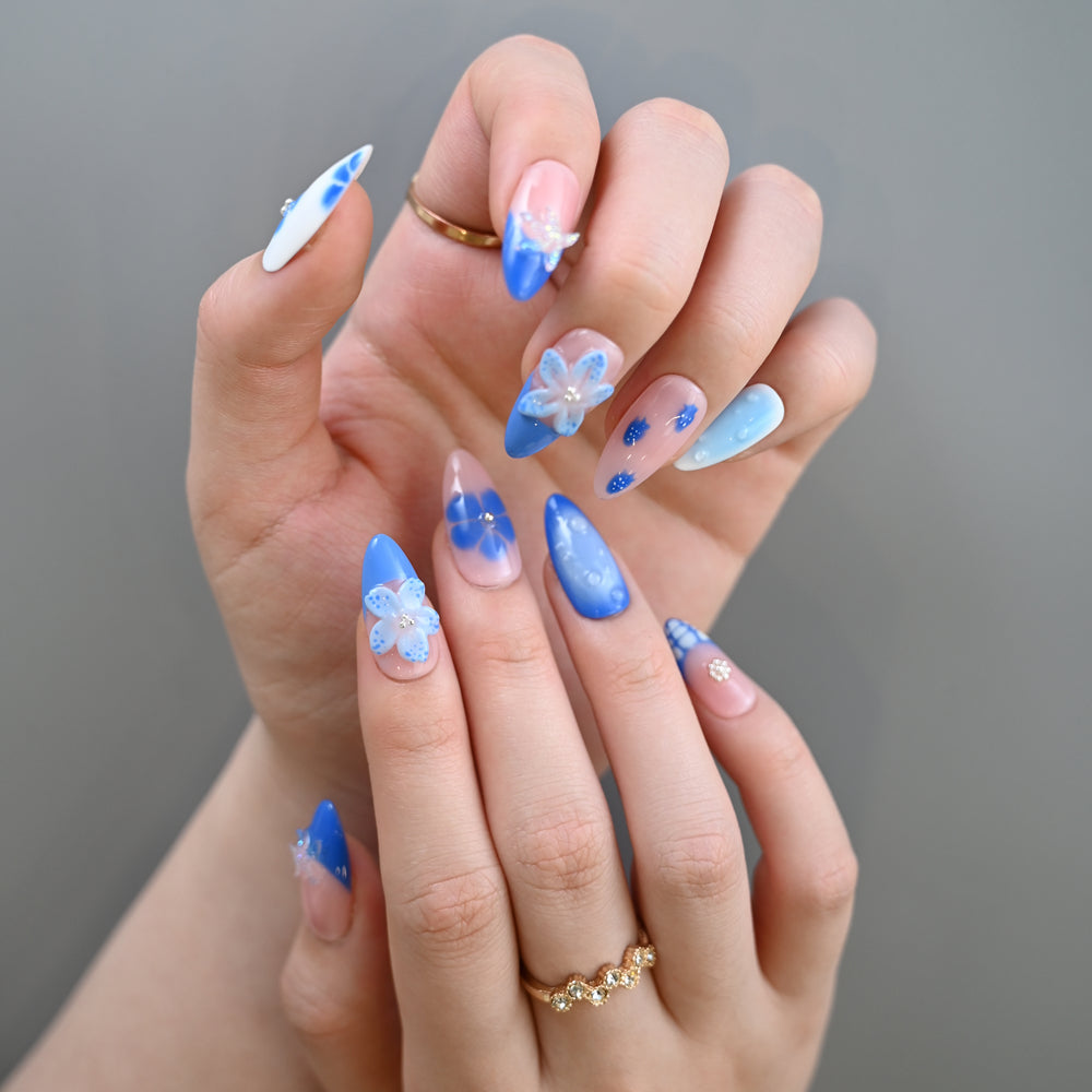 Ocean-inspired almond nails in pastel blue with seashell and flower accents