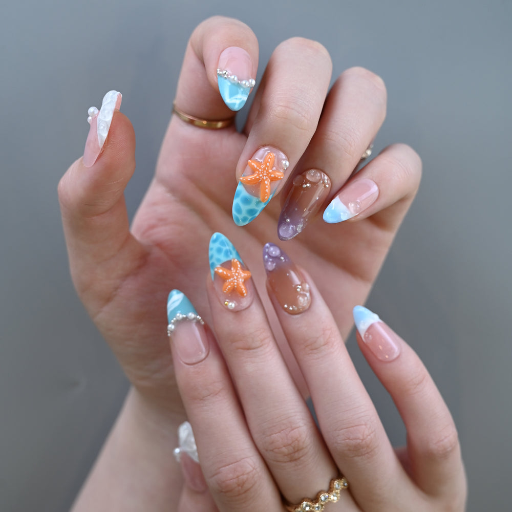 Beach style press-on nails featuring coral orange starfish and sea-inspired accents