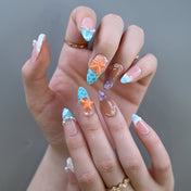 Beach style press-on nails featuring coral orange starfish and sea-inspired accents