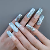 Luxury blue press-on nails featuring metal butterfly charms, silver rose, and pearl designs