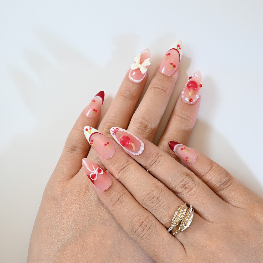 Sweet almond press-on nails with hand-painted cherries, big bow, and red tips