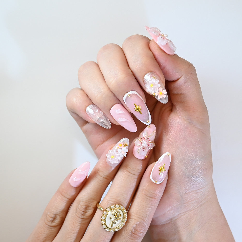 Sweet pink and white press-on nails with layered flowers, gold foil, and glitter details