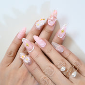 Cute pink floral press-on nails with pearly accents, gold details, and glitter finish