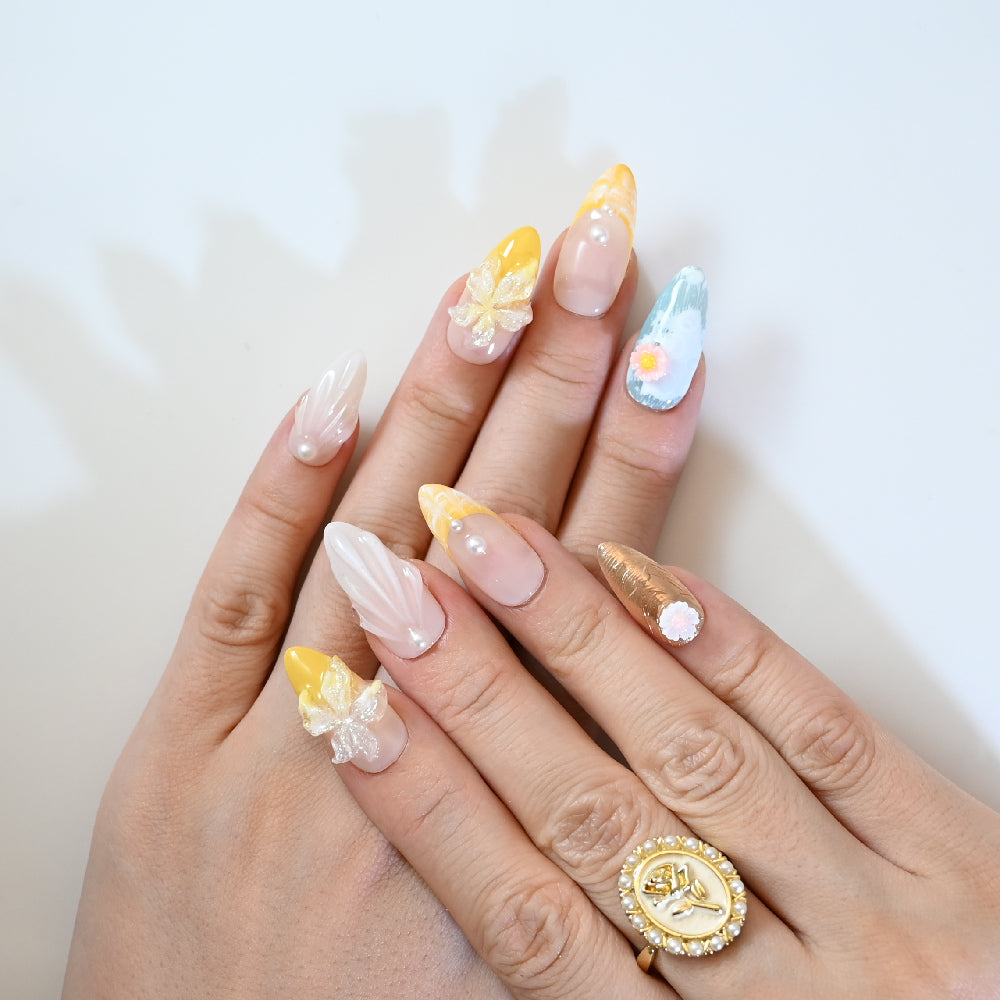 Elegant nude press-on nails with yellow floral design and gemstone pearls