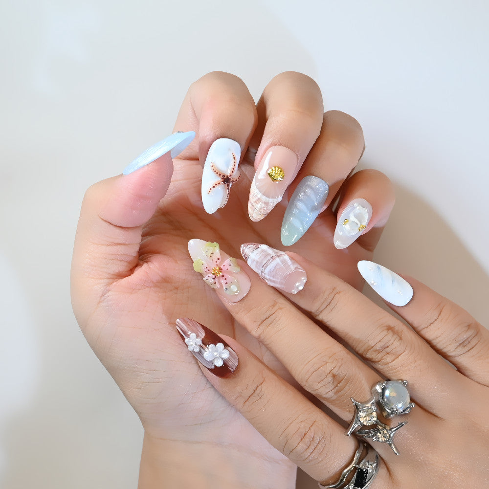 Tropical beach press-on nails with seashell decor, ocean blue tips, and floral accents