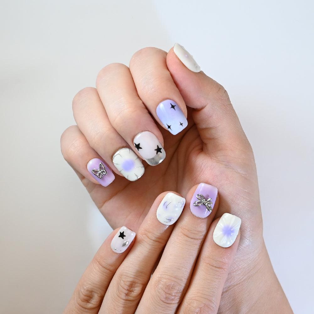 Square short press-on nails featuring dreamy lilac ombre, cosmic star accents, and 3D metal charms