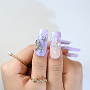 Pastel purple press-on nails with cross design, pearls, and floral art