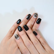 Handmade black press-on nails featuring abstract silver lines and cosmic star designs