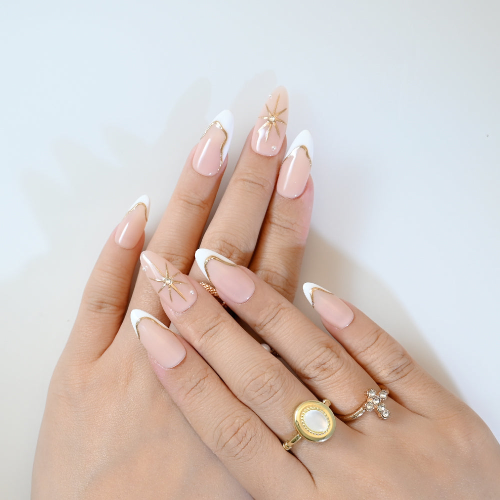 Chic press-on nails with white French tips, gold edges, and gemstone star details