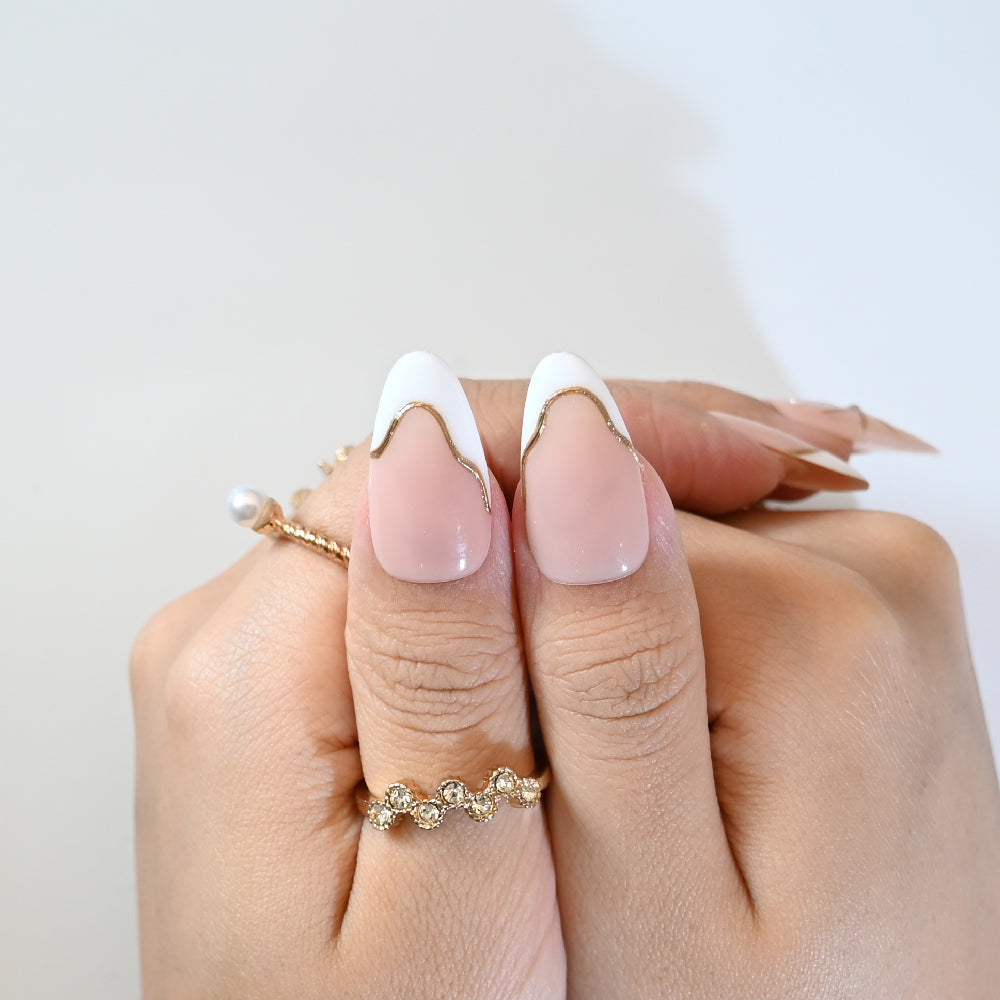 Elegant nude almond press-on nails with gold starburst accent and minimalist French tips