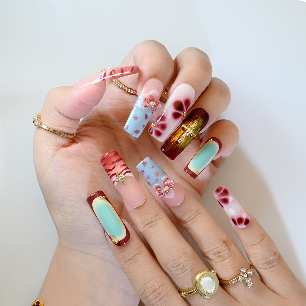 3D bow and floral press-on nails with deep red tones and gold embellishments