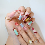 3D bow and floral press-on nails with deep red tones and gold embellishments