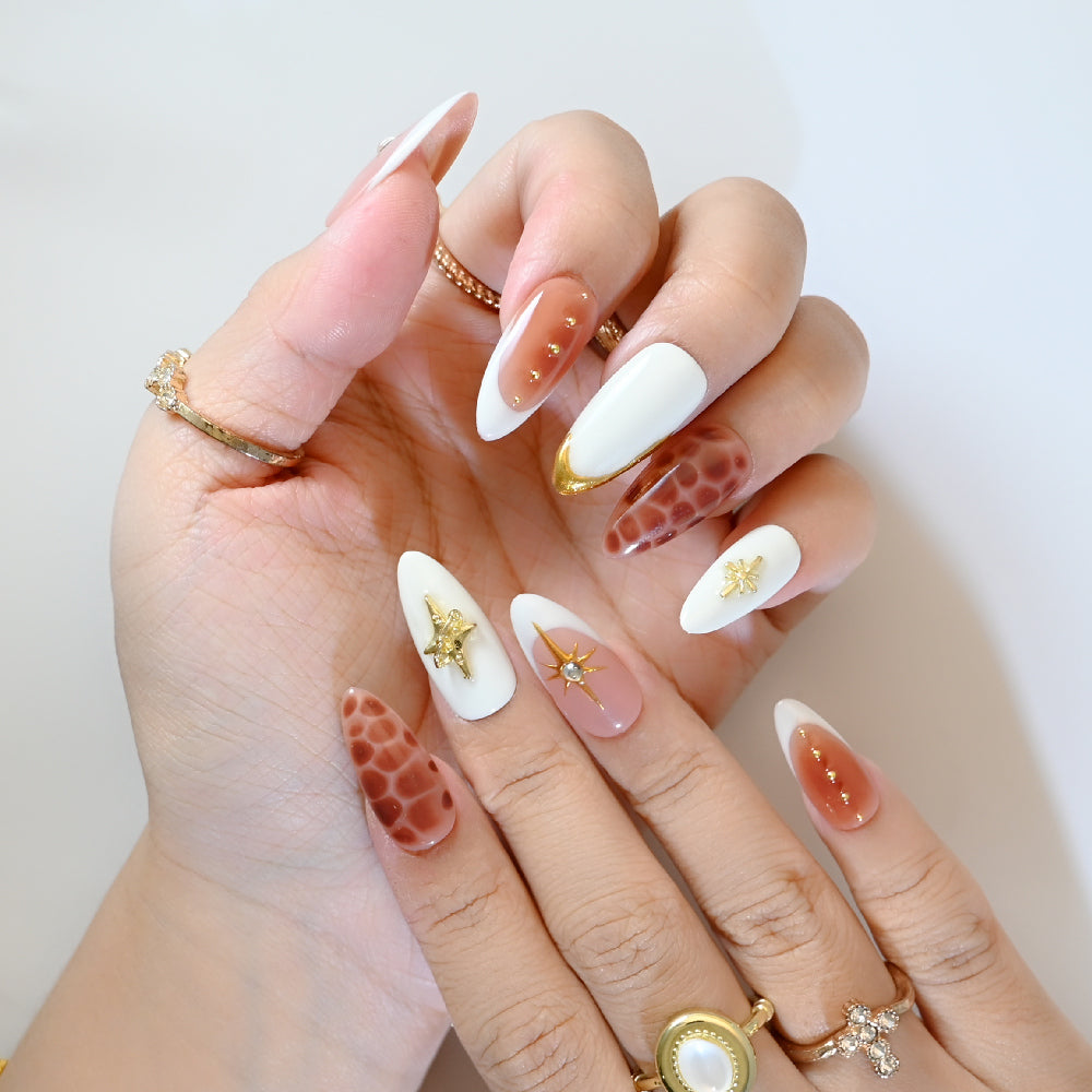 Elegant press-on nails with gold starburst design, gemstone accents, and giraffe print
