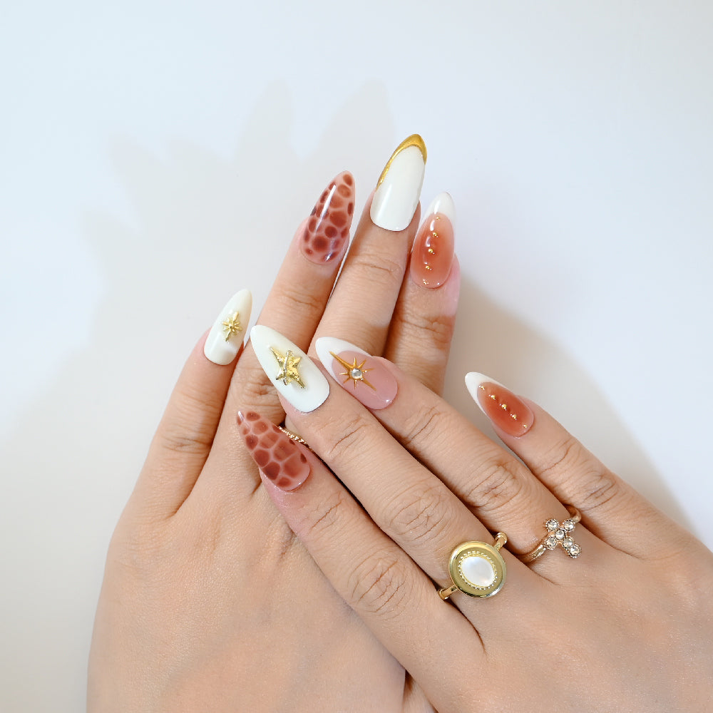 Stylish almond press-on nails with gold stars, crystal gems, and safari-inspired design