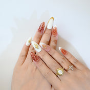 Stylish almond press-on nails with gold stars, crystal gems, and safari-inspired design