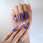 Color-block orange and purple stiletto nails with heart charms and 3D petals