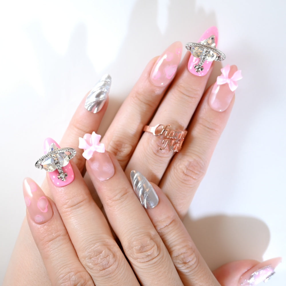 Nude and hot pink press-on nails with butterfly detail, bow accents, and silver tip