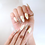 Luxury almond press-on nails with gold foil details, silver sparkle, and 3D pearl embellishments