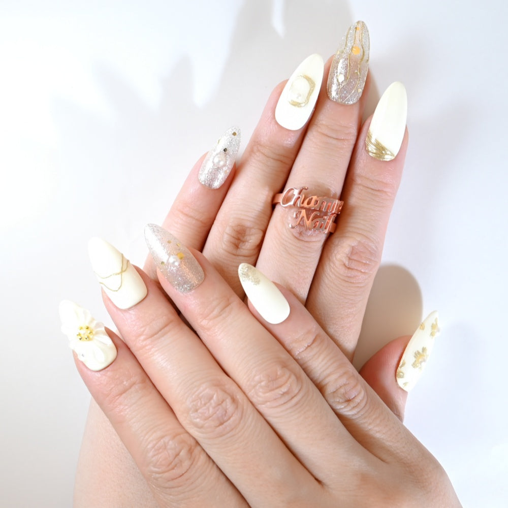 Chic metallic press-on nails with gold wave patterns, glitter accents, and delicate pearl designs