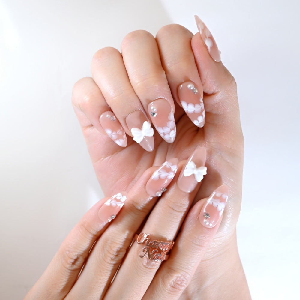 Handmade nude nails with white petals, pearls, and rhinestones