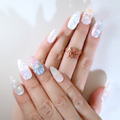 Ocean-inspired press-on nails with blue and pink shell design, pearl clusters, and glitter shine