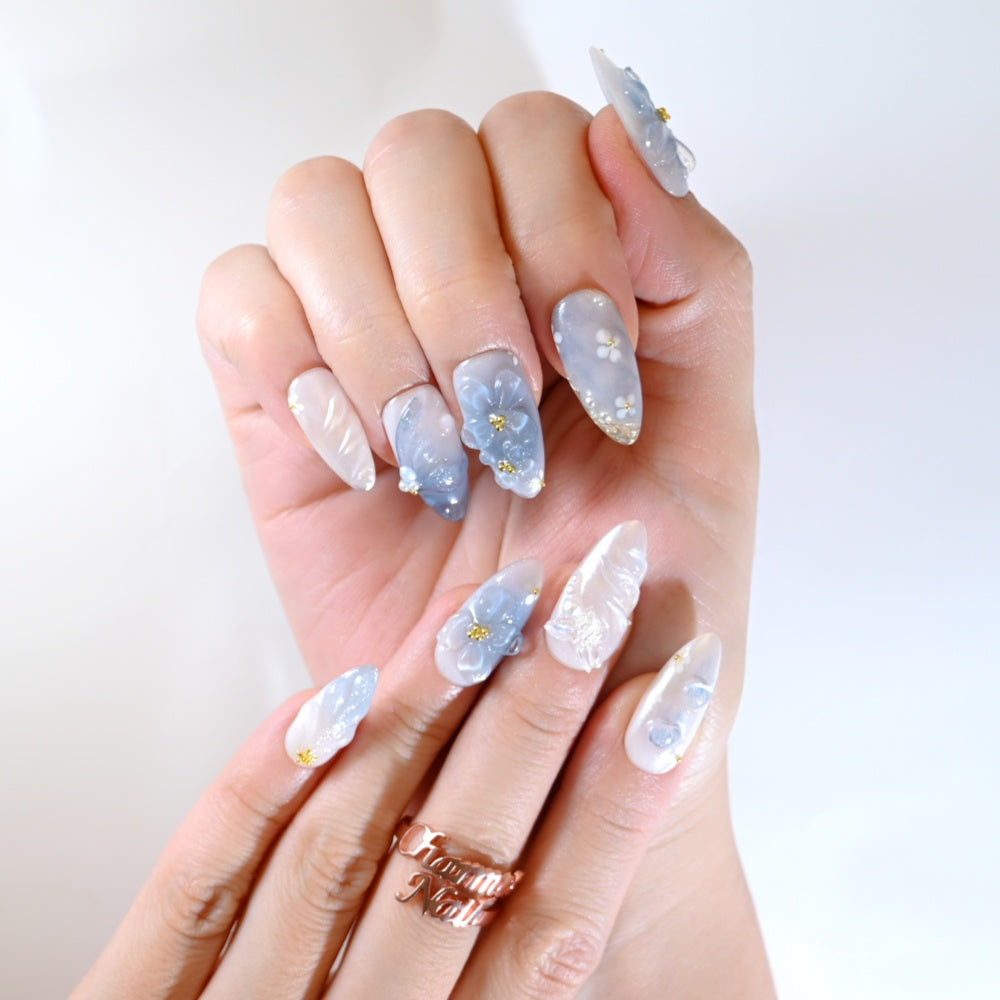Icy blue and white press-on nails with hand-sculpted flowers and shimmering details