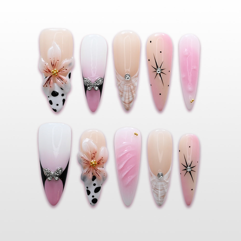 Pink and white ombre press-on nails with 3D flowers, butterfly charms, and starburst accents
