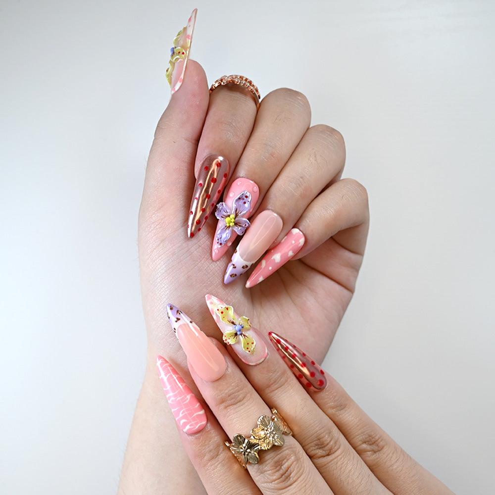 Pink stiletto press-on nails with 3D floral accents and playful dots