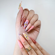 Pink stiletto press-on nails with 3D floral accents and playful dots