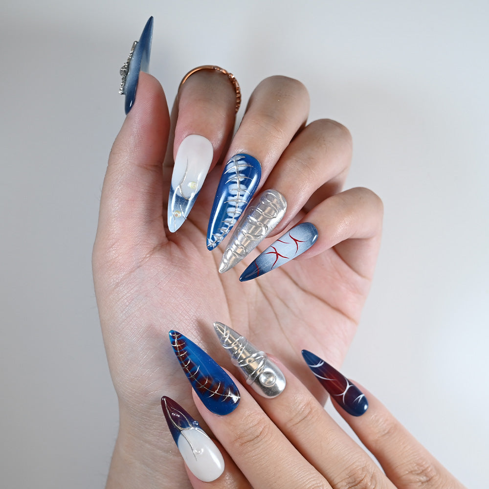 Long stiletto reusable press-on nails in deep blue, silver chrome and pearl cross accents