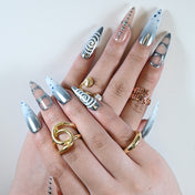 Metallic silver press-on nails with blue gradient, geometric cutouts, and swirl art