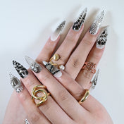 Handmade stiletto nails featuring rhinestones, animal print, and modern patterns