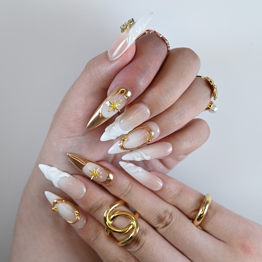 Elegant nude and metallic gold nails with 3D butterfly and star charm designs