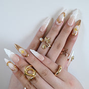 Handmade stiletto press-on nails with white sculpted tips and gold embellishments