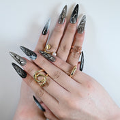 Metallic silver press-on nails featuring black accents and lightning-style patterns