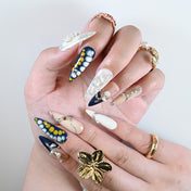 Elegant stiletto nails in blue, nude and white with 3D pearls, cross charm and silver metal details