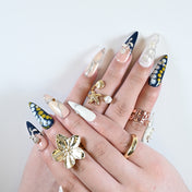 Luxury press-on nails featuring navy gradient, yellow dots, pearl embellishments and floral cross