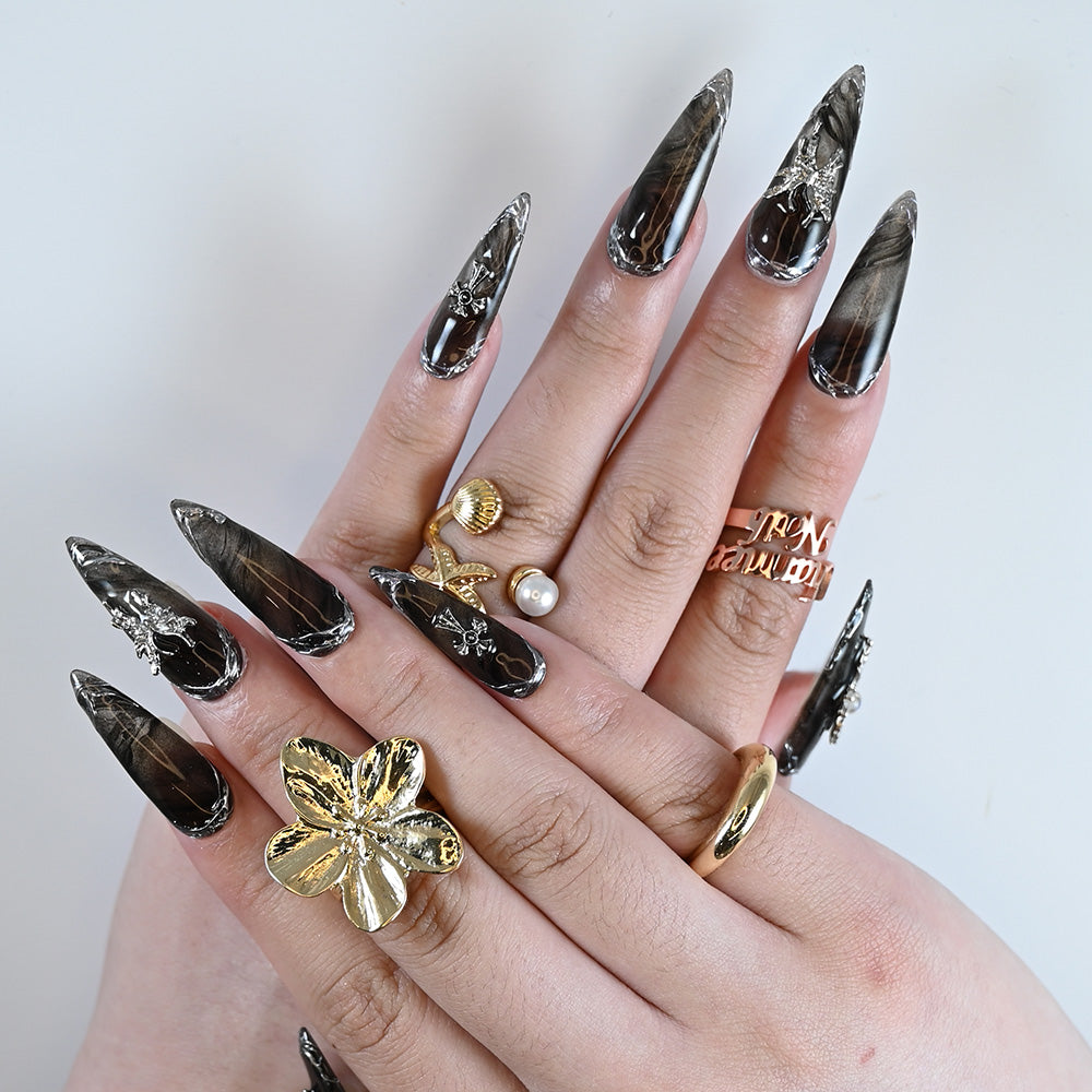 Handmade stiletto black marble nails with gothic cross and butterfly designs