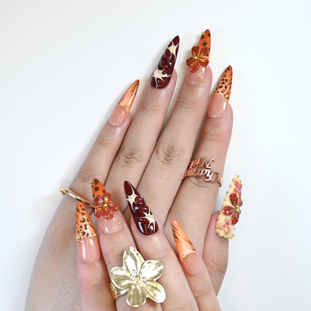 Safari theme press-on nails with leopard spots, deep red flowers, and bold patterns