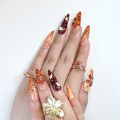 Safari theme press-on nails with leopard spots, deep red flowers, and bold patterns