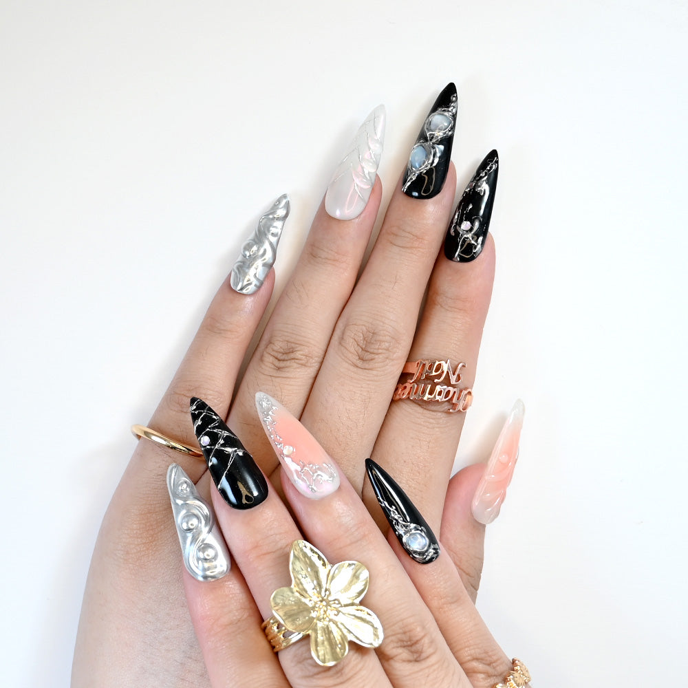 Edgy stiletto press-on nails in black and white with 3D metallic swirls and crystals