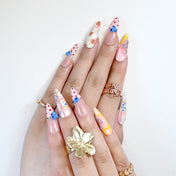Colorful spring nails with 3D blue blossoms, mixed patterns, and gradient pink base